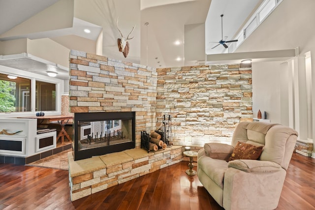 living room featuring wood-type flooring, high vaulted ceiling, ceiling fan, and a fireplace