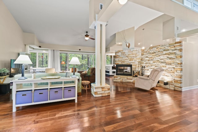 living area with high vaulted ceiling, a ceiling fan, wood finished floors, a fireplace, and ornate columns