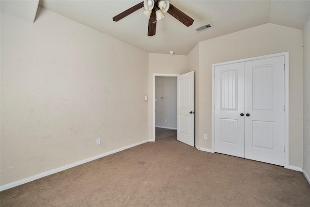 unfurnished bedroom with vaulted ceiling, ceiling fan, carpet, and a closet