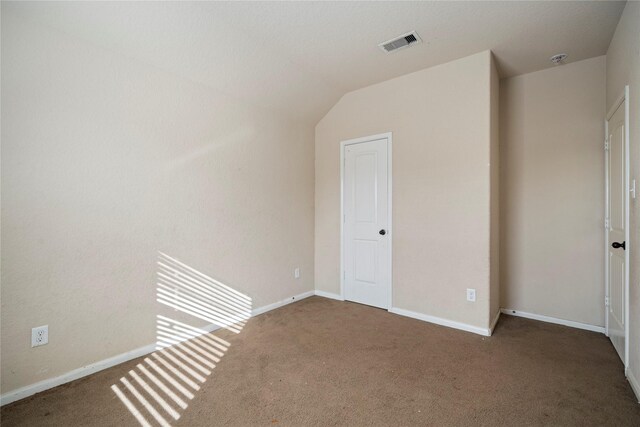 unfurnished room with carpet floors, baseboards, lofted ceiling, and visible vents