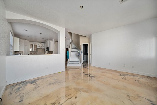 unfurnished living room with stairs, baseboards, and concrete floors