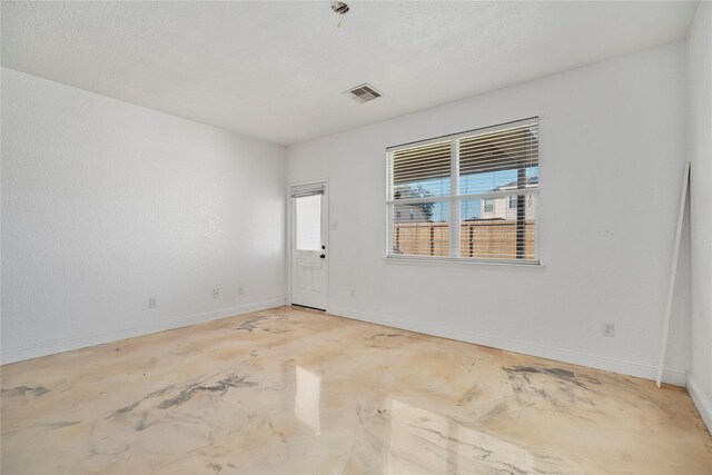 spare room featuring visible vents, baseboards, and concrete flooring