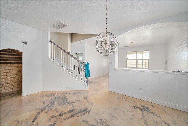interior space with visible vents, arched walkways, concrete flooring, an inviting chandelier, and stairs