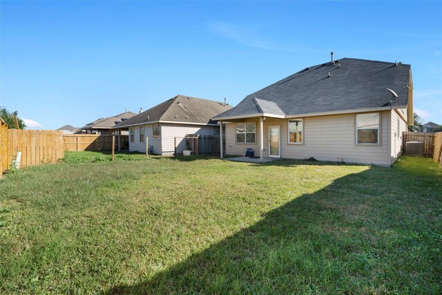 back of house featuring a lawn, a fenced backyard, and central AC