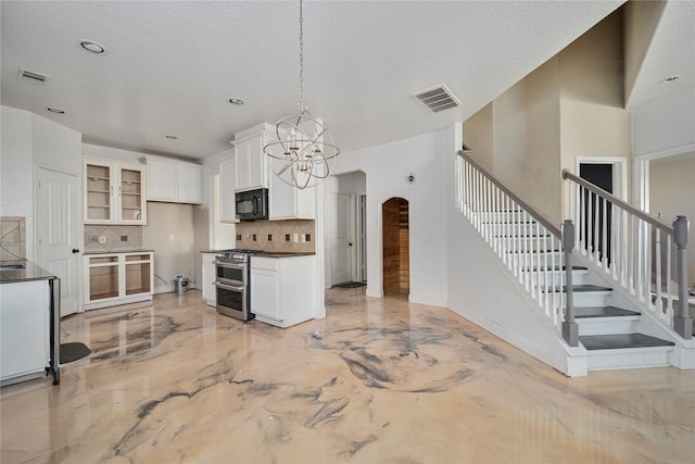 kitchen with decorative backsplash, white cabinetry, hanging light fixtures, range with two ovens, and a textured ceiling