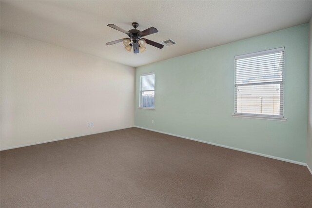 carpeted spare room with visible vents, a ceiling fan, and baseboards