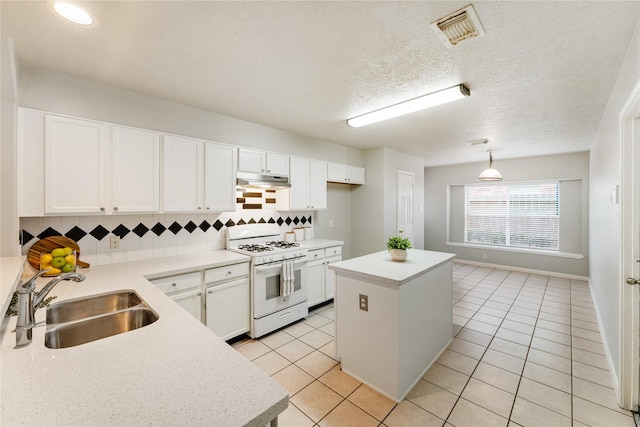 kitchen with sink, white cabinets, white gas range, tasteful backsplash, and a kitchen island