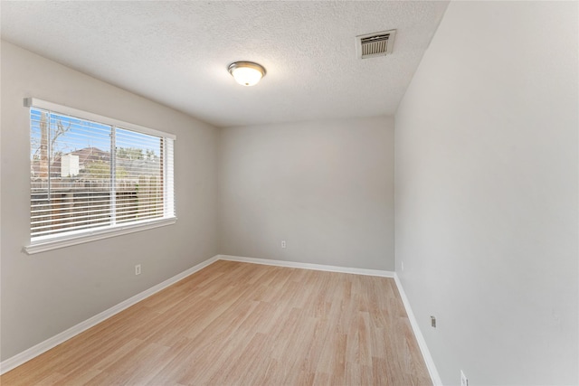 empty room with a textured ceiling and light wood-type flooring