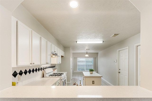 kitchen with kitchen peninsula, white gas range, decorative light fixtures, white cabinetry, and light tile patterned flooring