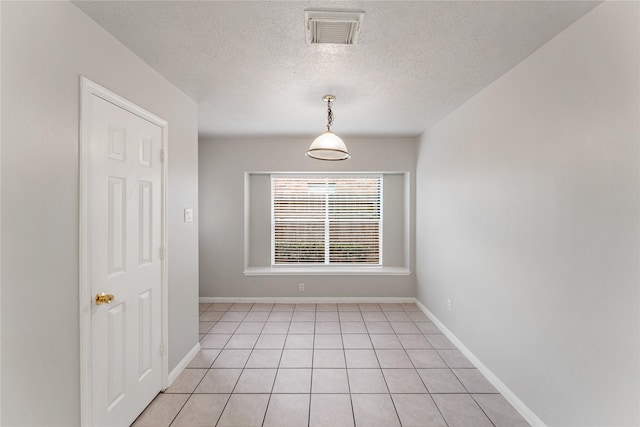 empty room featuring light tile patterned flooring and a textured ceiling