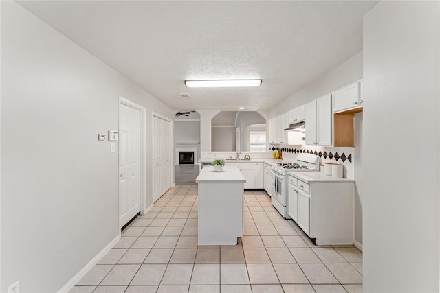 kitchen with a center island, white range with gas cooktop, a textured ceiling, white cabinetry, and sink