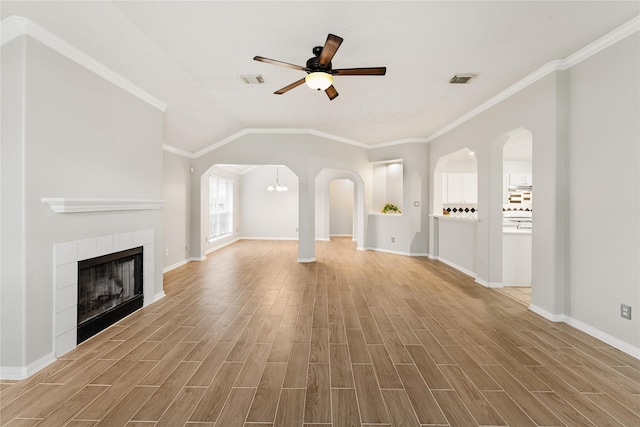 unfurnished living room featuring ornamental molding, ceiling fan with notable chandelier, vaulted ceiling, and a fireplace