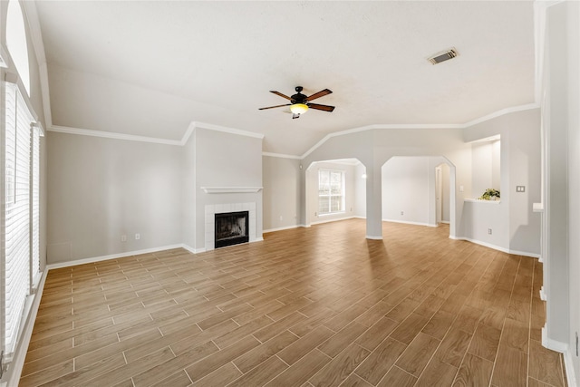 unfurnished living room featuring a tile fireplace, ceiling fan, a healthy amount of sunlight, and ornamental molding