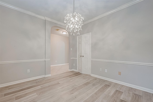 empty room featuring crown molding, light hardwood / wood-style flooring, and a chandelier