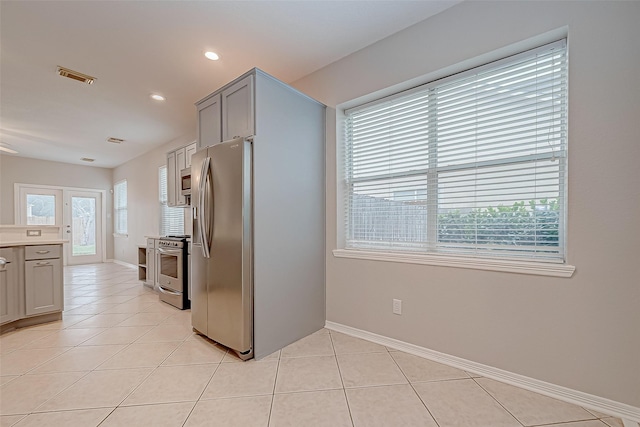 kitchen featuring light tile patterned floors, gray cabinetry, and appliances with stainless steel finishes