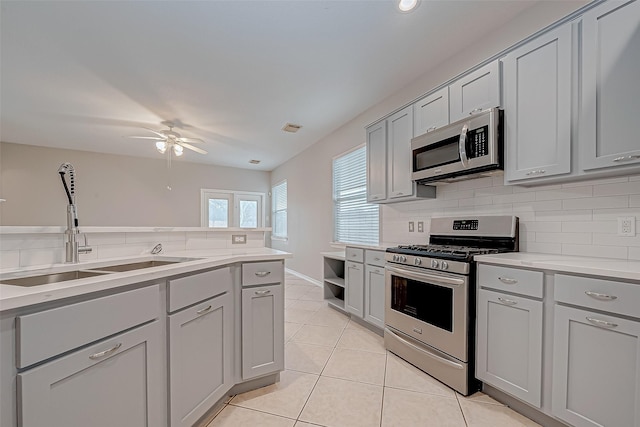 kitchen with stainless steel appliances, ceiling fan, light tile patterned floors, tasteful backsplash, and gray cabinets