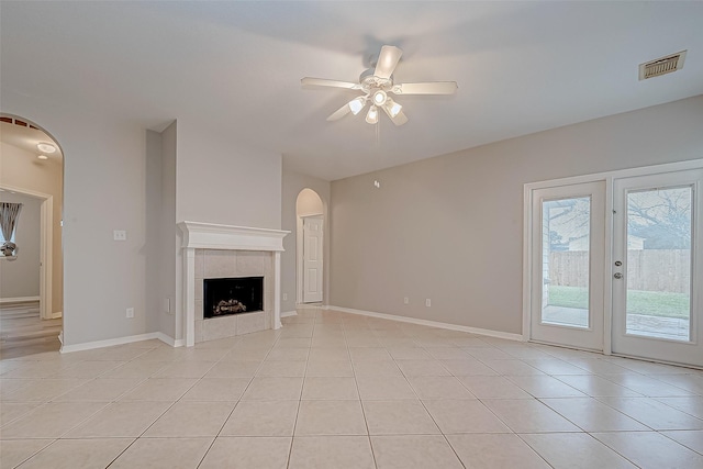 unfurnished living room with a fireplace, ceiling fan, and light tile patterned floors