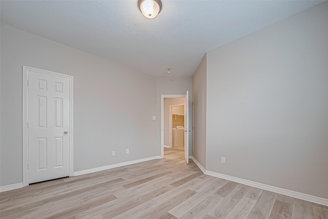 spare room with washer and dryer, a textured ceiling, and light wood-type flooring