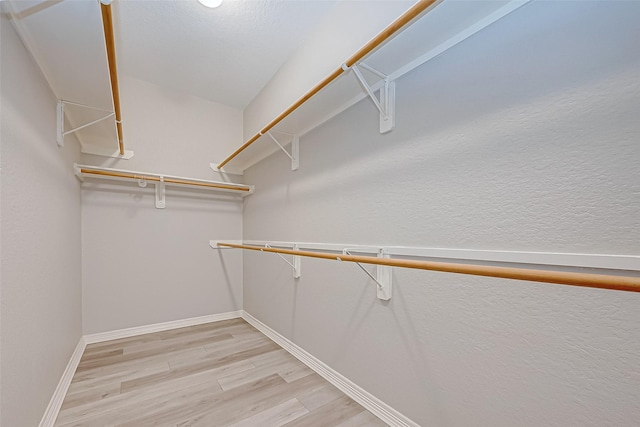 walk in closet with light hardwood / wood-style floors