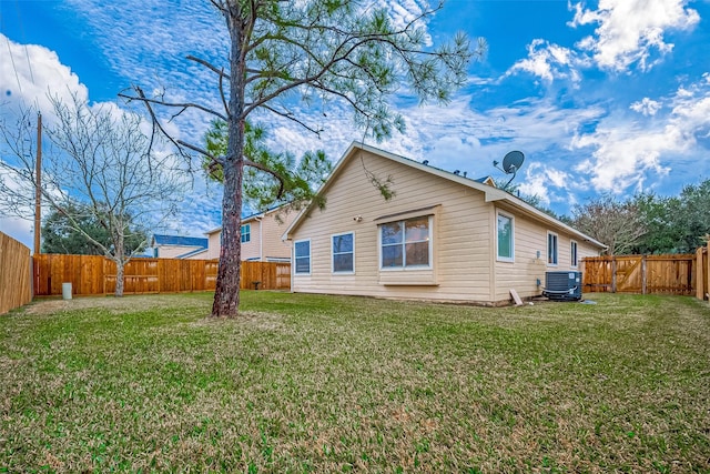 rear view of property featuring a yard and cooling unit