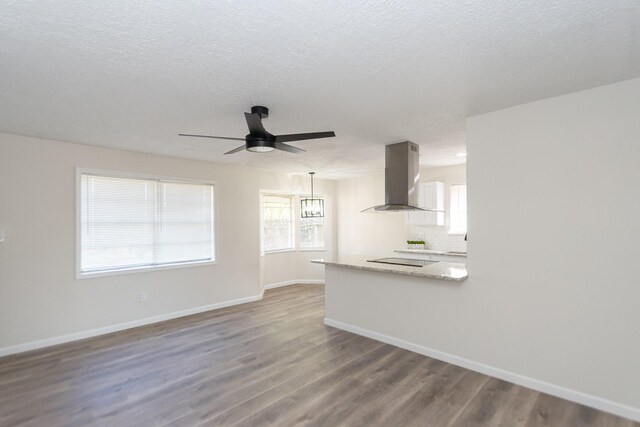 kitchen featuring ceiling fan with notable chandelier, decorative light fixtures, island exhaust hood, and hardwood / wood-style floors