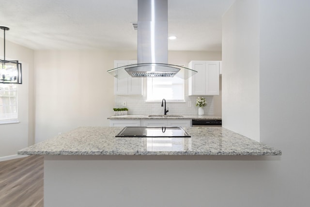 kitchen with sink, white cabinets, decorative light fixtures, light stone counters, and island exhaust hood