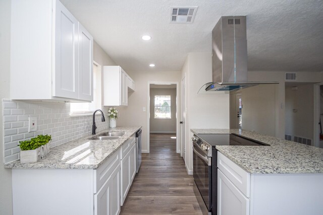 kitchen with white cabinets, appliances with stainless steel finishes, light stone countertops, and island exhaust hood