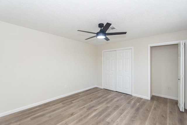 unfurnished bedroom with a textured ceiling, ceiling fan, light hardwood / wood-style flooring, and a closet