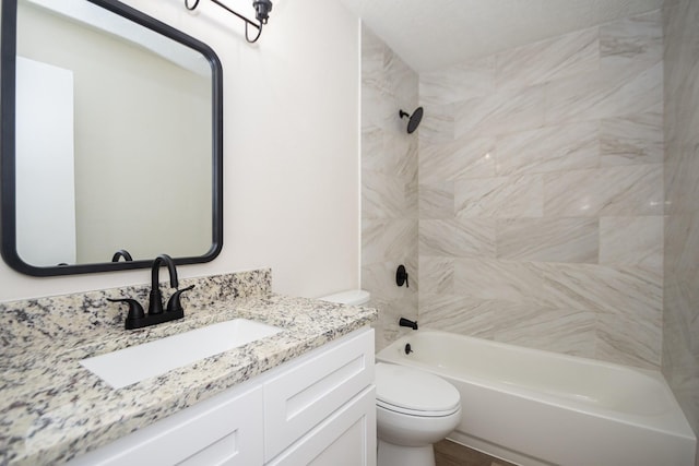 full bathroom featuring vanity, tiled shower / bath combo, and toilet