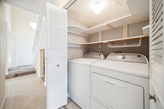 washroom with washer and dryer, light tile patterned floors, and a textured ceiling