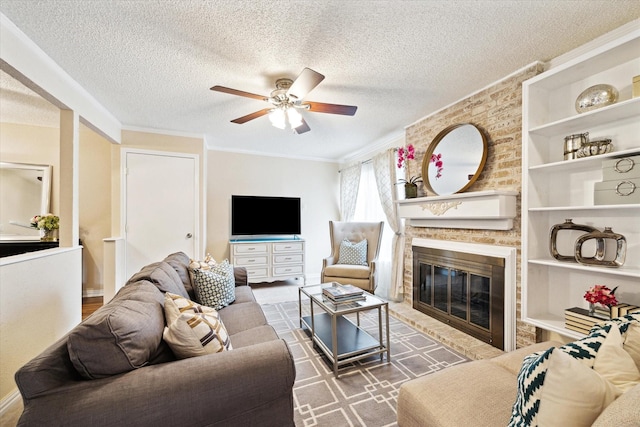 living room featuring built in shelves, crown molding, a brick fireplace, a textured ceiling, and ceiling fan