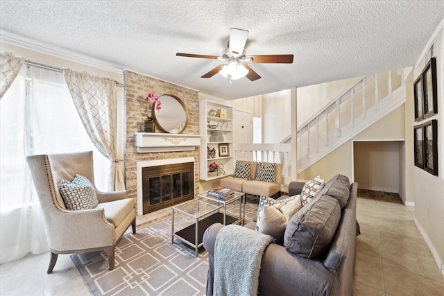 tiled living area with a brick fireplace, stairs, a ceiling fan, and a textured ceiling