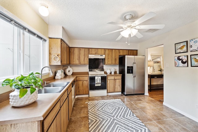 kitchen featuring sink, ceiling fan, appliances with stainless steel finishes, a textured ceiling, and decorative backsplash