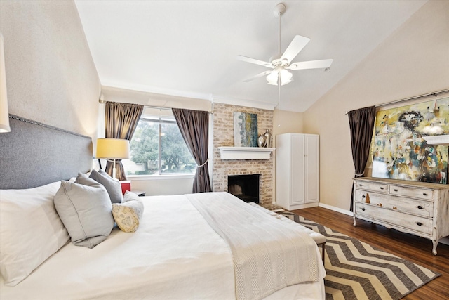 bedroom with ceiling fan, lofted ceiling, dark hardwood / wood-style floors, and a brick fireplace