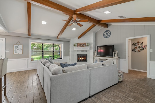 living room with a brick fireplace, lofted ceiling with beams, and ceiling fan