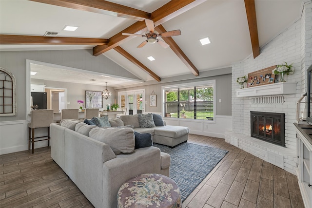 living room with a fireplace, ceiling fan, and vaulted ceiling with beams