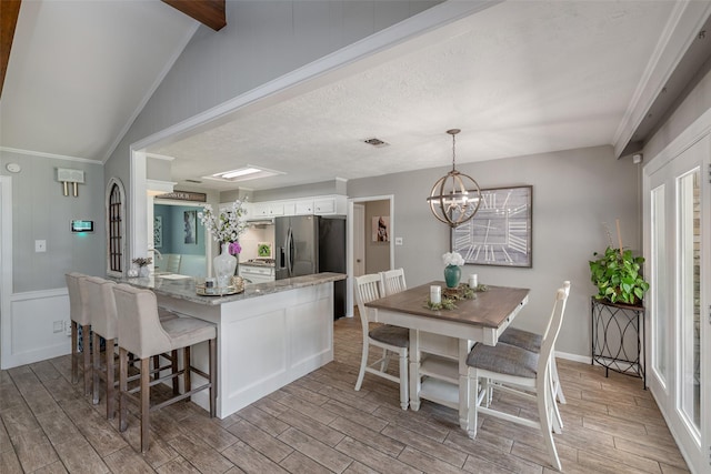 kitchen featuring light stone countertops, decorative light fixtures, a notable chandelier, stainless steel fridge, and white cabinetry