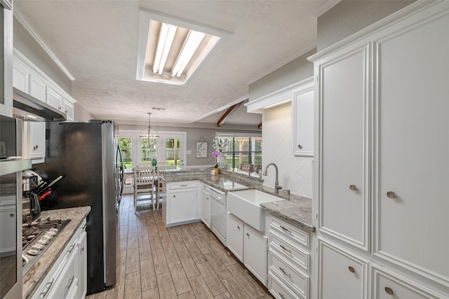 kitchen featuring kitchen peninsula, decorative light fixtures, white cabinetry, white dishwasher, and sink