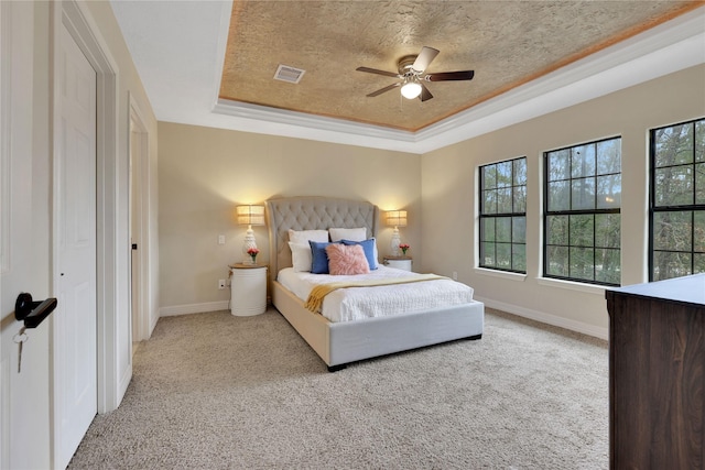 bedroom featuring light carpet, ceiling fan, a raised ceiling, a textured ceiling, and ornamental molding