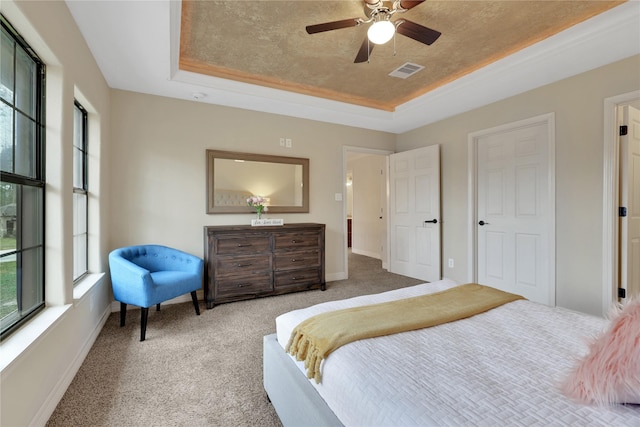 bedroom with ceiling fan, carpet floors, and a tray ceiling