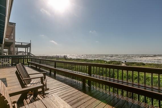 wooden deck with a water view and a beach view