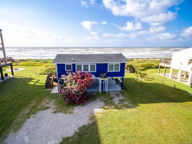 exterior space with a view of the beach, a lawn, and a water view