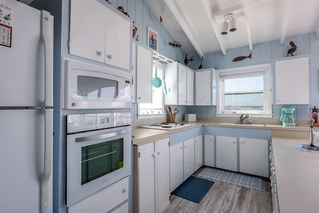 kitchen with sink, light wood-type flooring, beamed ceiling, white appliances, and white cabinets