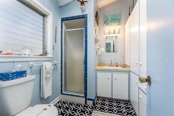 bathroom featuring toilet, vanity, and a shower with shower door