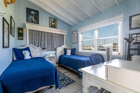 bedroom featuring hardwood / wood-style floors and vaulted ceiling with beams