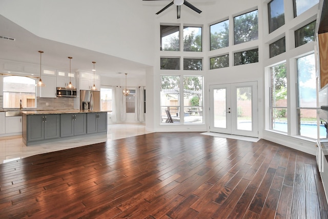 unfurnished living room with a high ceiling, french doors, and wood-type flooring