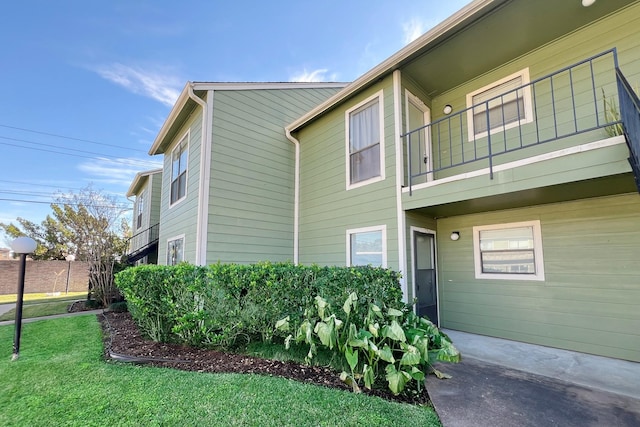 view of property exterior featuring a balcony and a yard