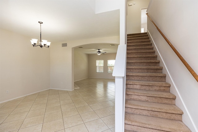 stairway with tile patterned flooring and ceiling fan with notable chandelier