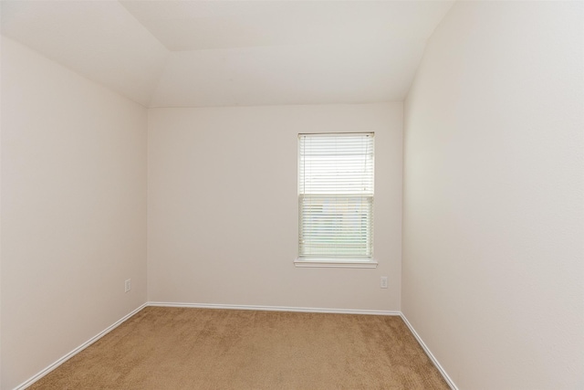 carpeted spare room with vaulted ceiling