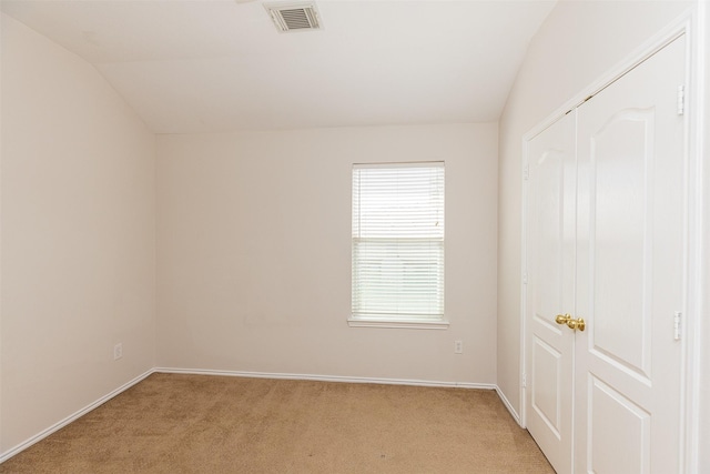 carpeted spare room with lofted ceiling